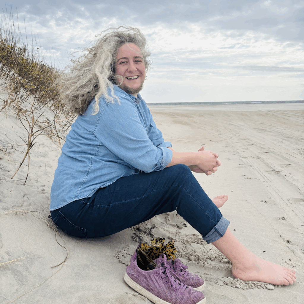 Jessica sitting on the beach, smiling at the camera