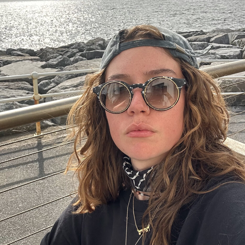 A selfie of Em, with rocks and water in the background